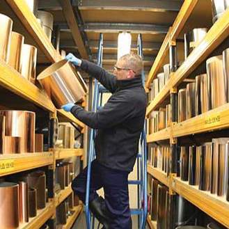 A worker examines a roll of copper metal